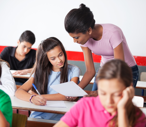 Teacher showing paper to teenage girl during examination in classroom