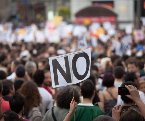 Photo of a protestor with a "no" sign