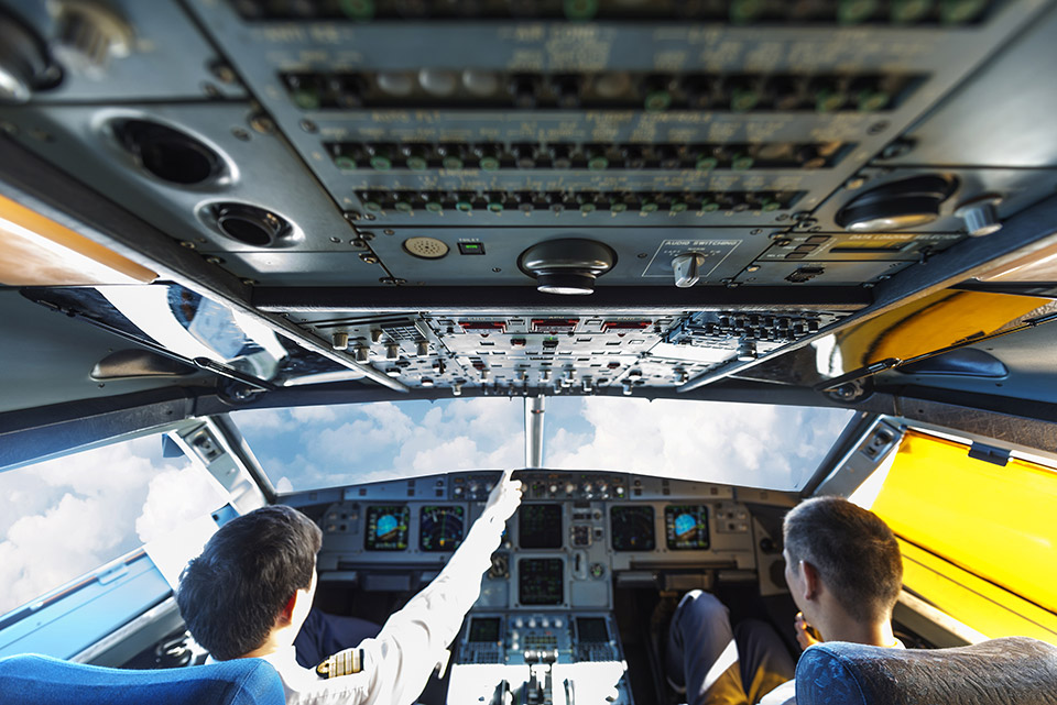 Completing a Writing "Systems Check" Pilots interacting in a plane cockpit