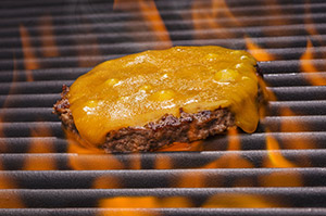 Cheeseburger cooking on a flaming grill