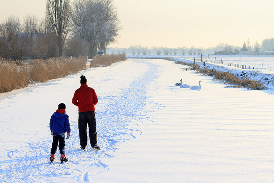 Two ice skaters glide along a frozen river