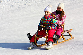 Photo of two young girls sledding