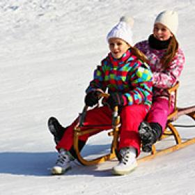 Photo of two young girls sledding