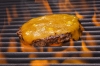 Cheeseburger cooking on a flaming grill
